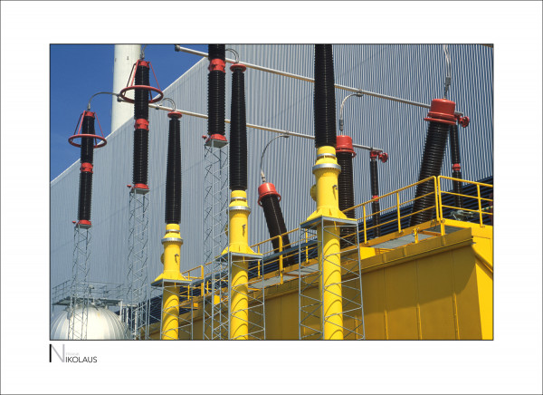 INDUSTRIEFOTOGRAFIE 3 Gelbe Isolatoren vor einer Stahlfassade