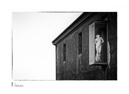 Glaskasten mit klassischer Aktskulptur an der Burgfassade Savona