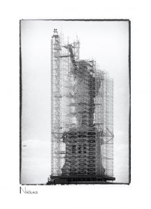 Eingerüstete Freiheitsstatue mit Flugzeug im Hintergrund in New York